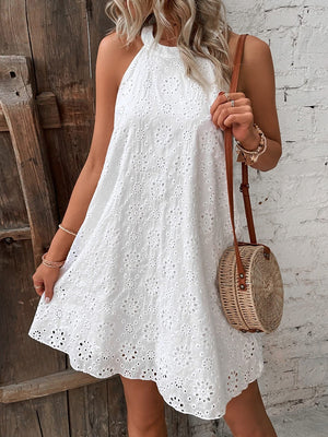 White eyelet halter trapeze dress with floral details and a trapeze cut.