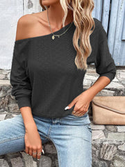 Black off-shoulder eyelet knit blouse with long sleeves and a diamond pattern.