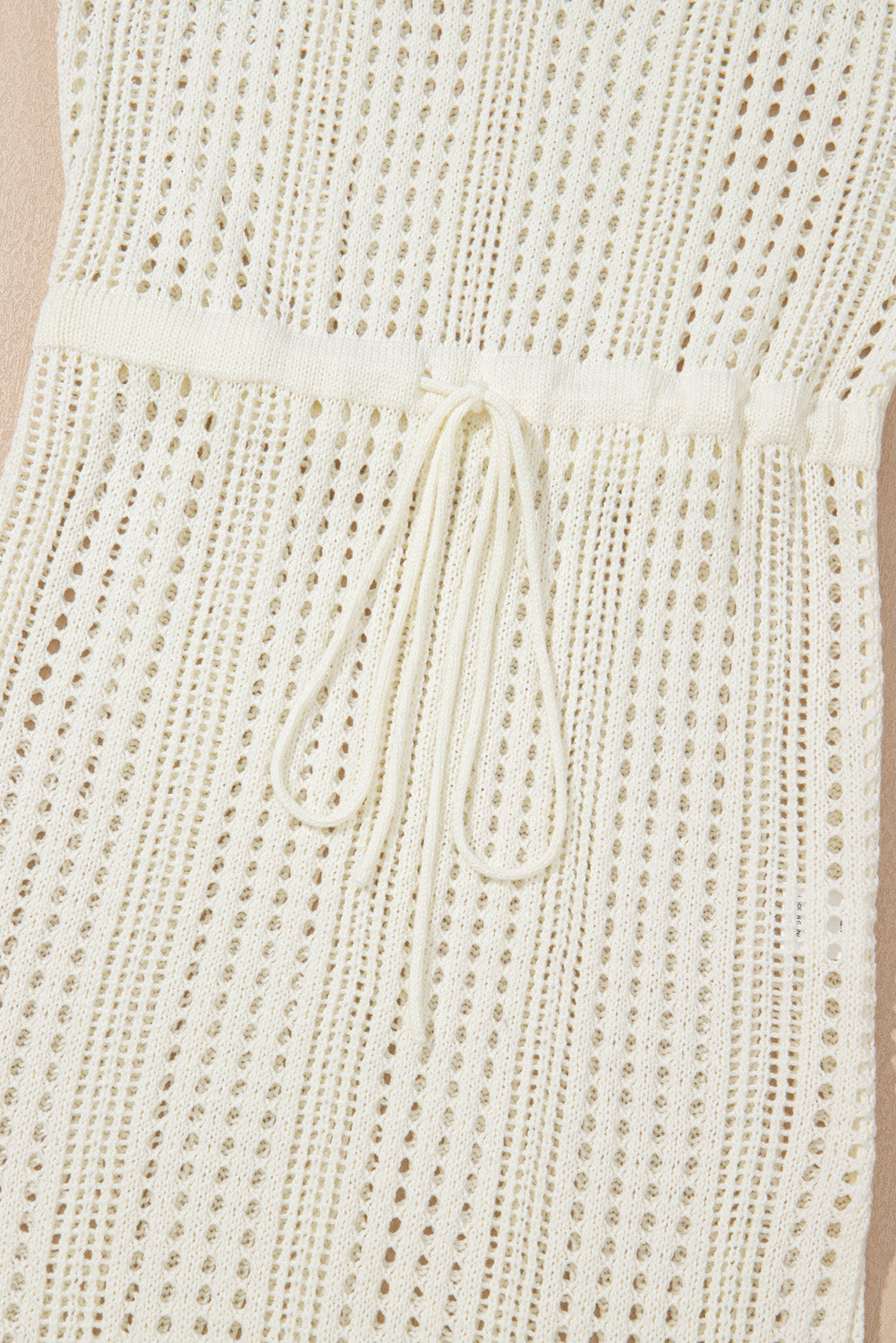 Beige open-knit mini dress with drawstring waist and breathable acrylic fabric.
