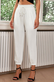 White cropped joggers with pleated waistband and drawstring detail