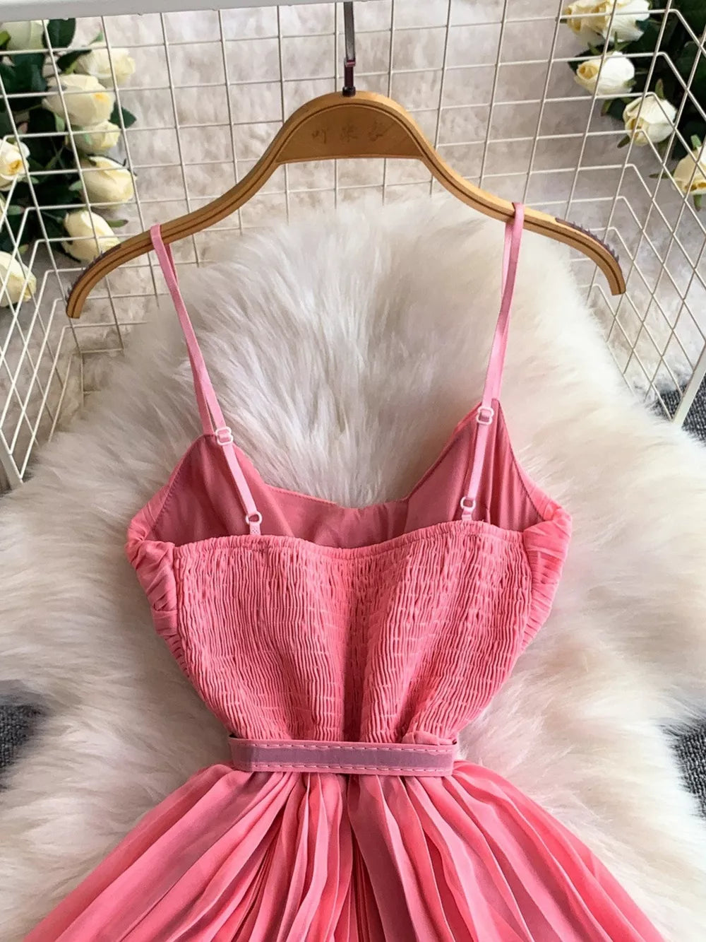 Pink belted midi dress with spaghetti straps and smocked bodice.