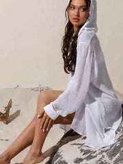 White oversized linen hooded shirt dress with button details and long sleeves.