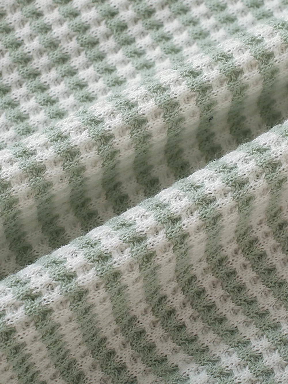Light green and white striped baby knit set fabric detail.