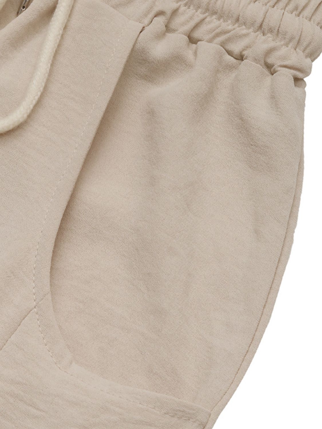 Tan palazzo trousers with drawstring waist and pockets, made from breathable fabric.