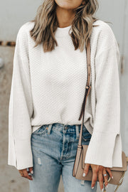 White textured knit sweater with crew neck and split sleeves, styled with jeans.