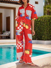 Orange-red camp shirt and wide-leg pants set with a colorful tropical fruit print.