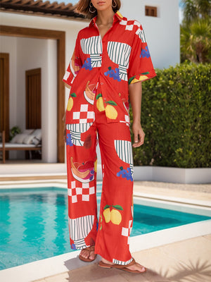 Orange-red camp shirt and wide-leg pants set with a colorful tropical fruit print.