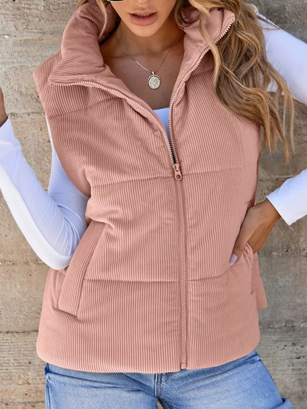 Pink ribbed corduroy zip-up vest coat with stand-up collar and pockets.