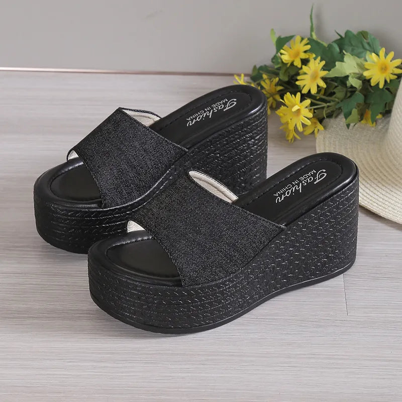 Black denim platform wedge slides with a textured wedge heel.