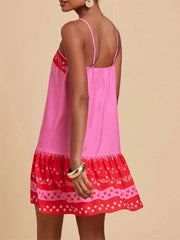 Pink spaghetti strap mini dress with a tiered red hem featuring a playful fish and floral print.
