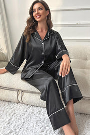 Black satin pajama set with white contrast trim, long sleeves and pants.