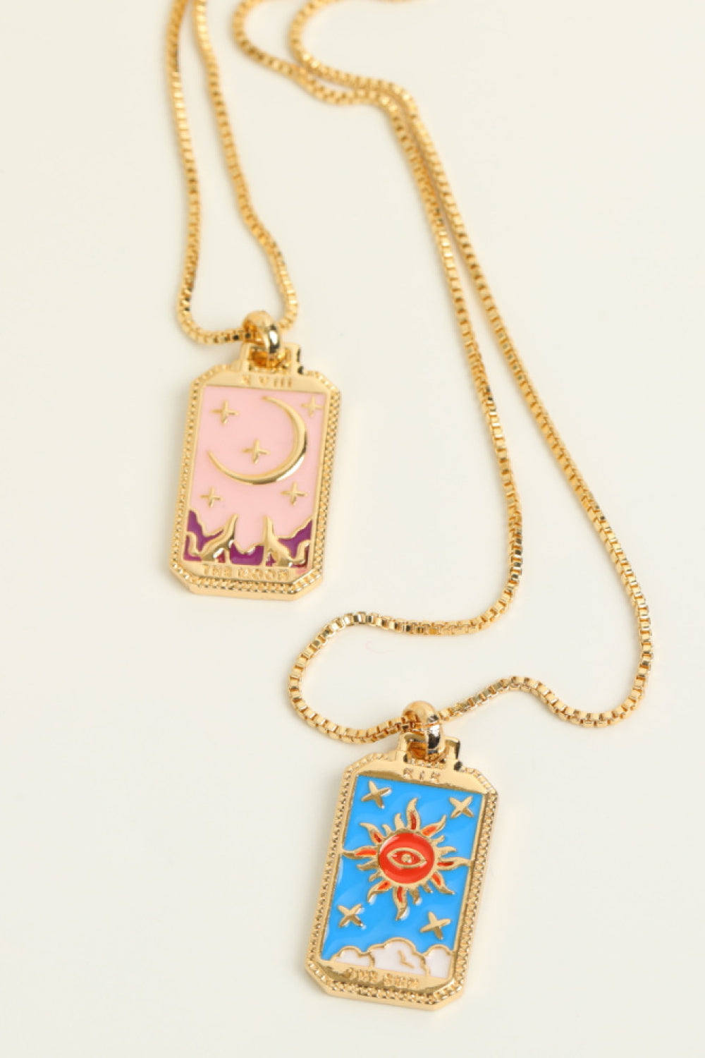Celestial tarot pendant necklace set with sun and moon charms on gold chains.