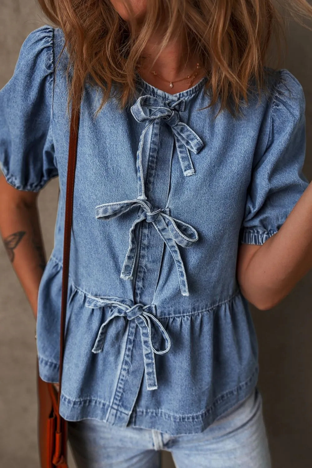 Denim peplum blouse with puff sleeves and multiple bow tie details.