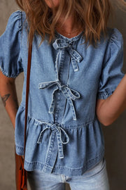 Denim peplum blouse with puff sleeves and multiple bow tie details.