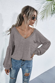 Dark gray knit top with V-neck, blouson sleeves, and chest pocket.