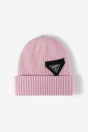 Pink ribbed acrylic beanie with a black triangle patch that says HAPPY