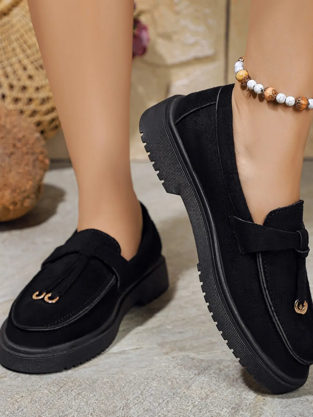 Black suede loafer slides with tassel detail and platform sole.