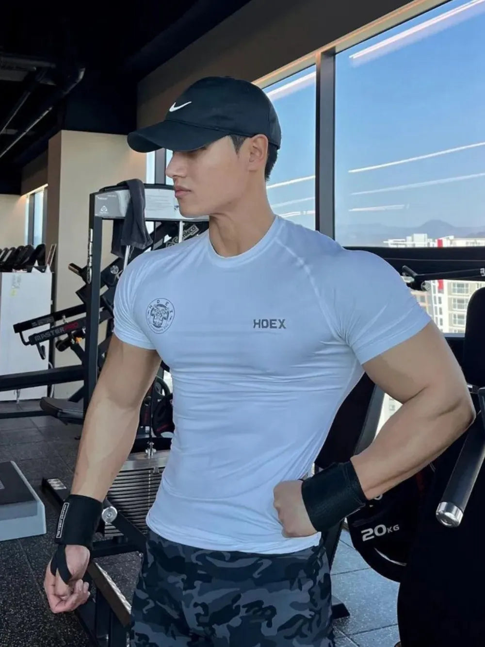 White crew neck athletic tee with HOEX logo, worn by a man in a gym.