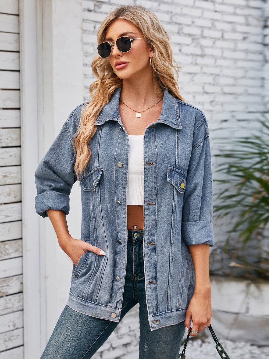 Oversized denim trucker jacket in dusty blue with rolled sleeves and button details.