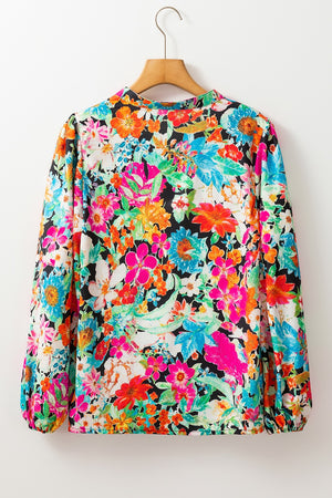 Vibrant floral print blouse with long sleeves and tassel trim detail.