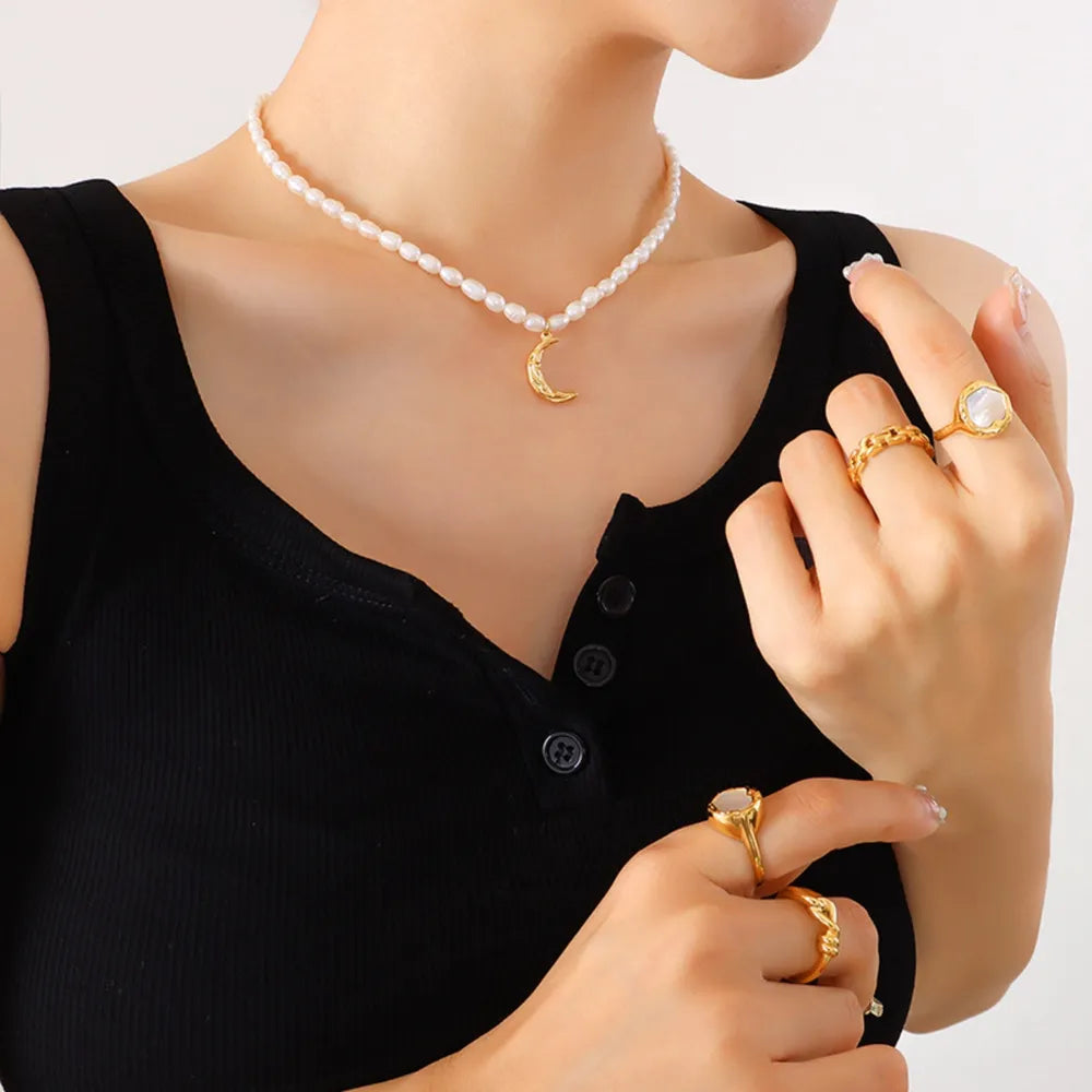 Gold crescent moon necklace with pearls, styled with rings