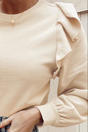 Cream sweatshirt with ruffled shoulder detail and ribbed cuffs.
