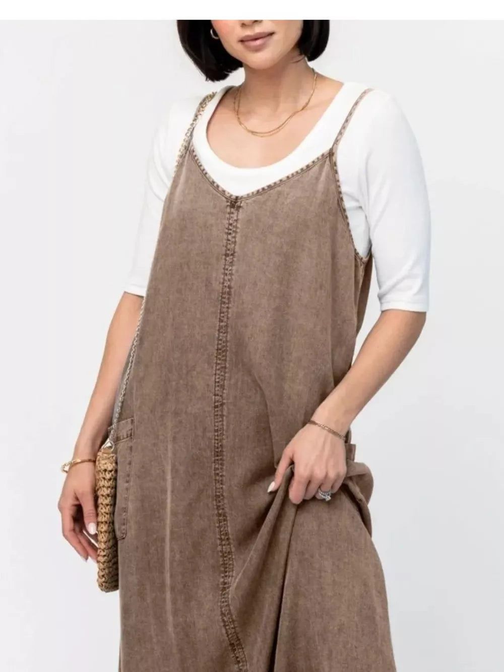 Brown washed denim maxi dress with V-neck and adjustable straps, layered over a white tee.