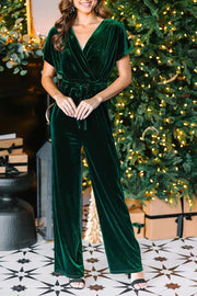 Dark green velvet wrap bodice jumpsuit with short sleeves and wide legs, cinched waist.