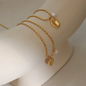 Gold oval medallion and pearl accent necklace with beaded chain.