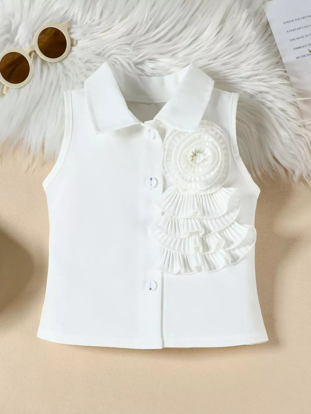 White collared sleeveless top with decorative ruffles and button detail.