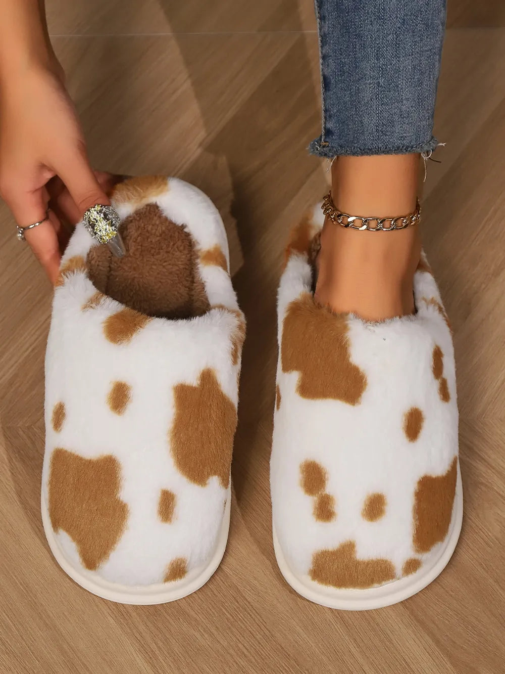 Cow print faux fur house slides in camel and white, with plush brown lining.