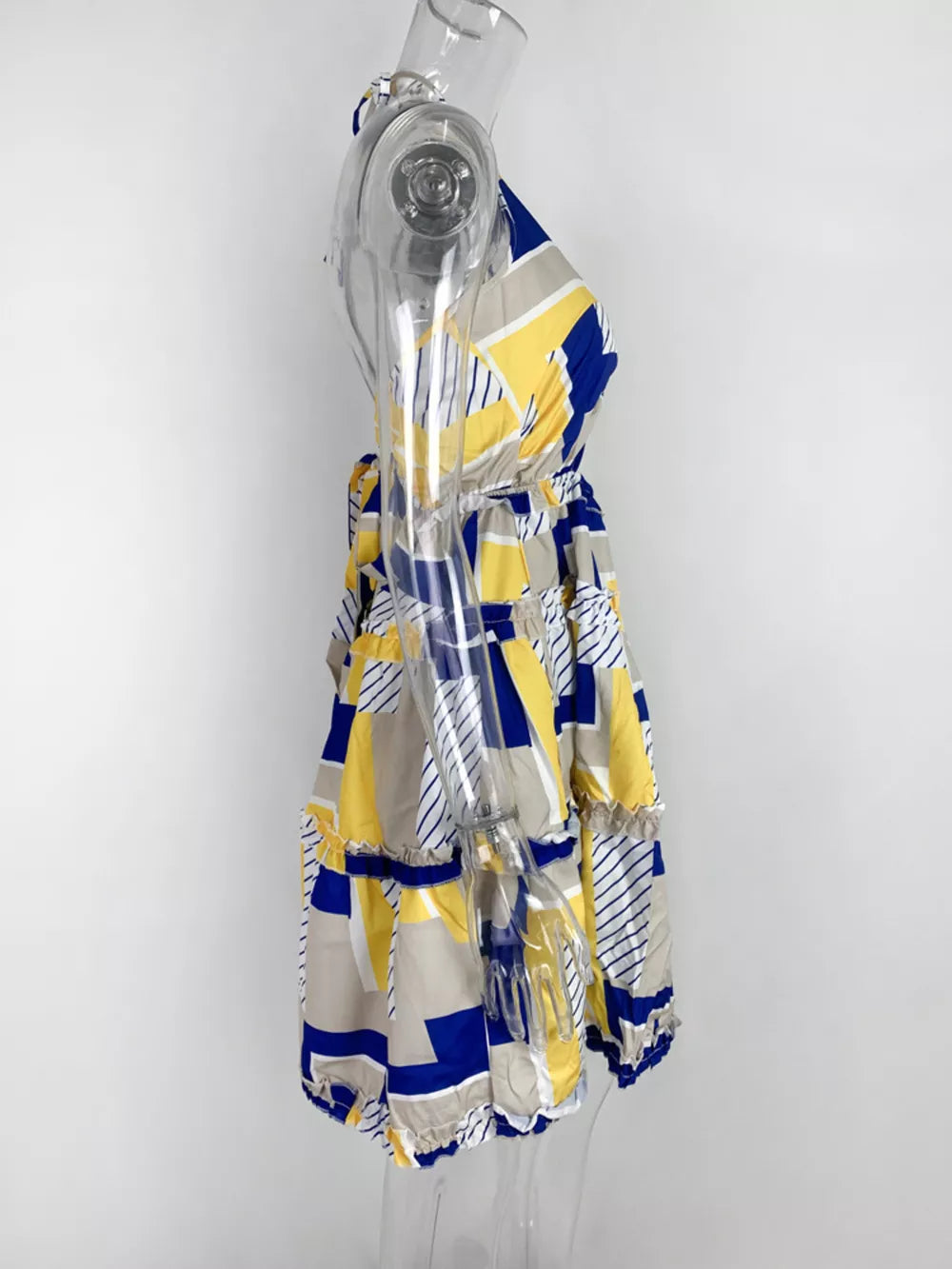 Abstract print halter mini dress with yellow, blue, and gray geometric pattern and tiered ruffles.