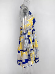 Abstract print halter mini dress with yellow, blue, and gray geometric pattern and tiered ruffles.