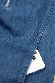 Denim shift dress with zip neck and side pocket holding a smartphone