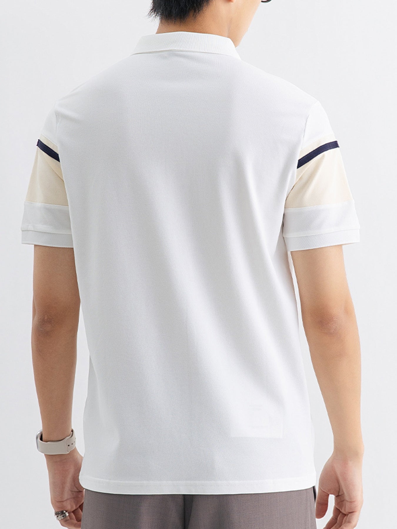 Men's white cotton polo with color block sleeves featuring navy and sherbet accents.