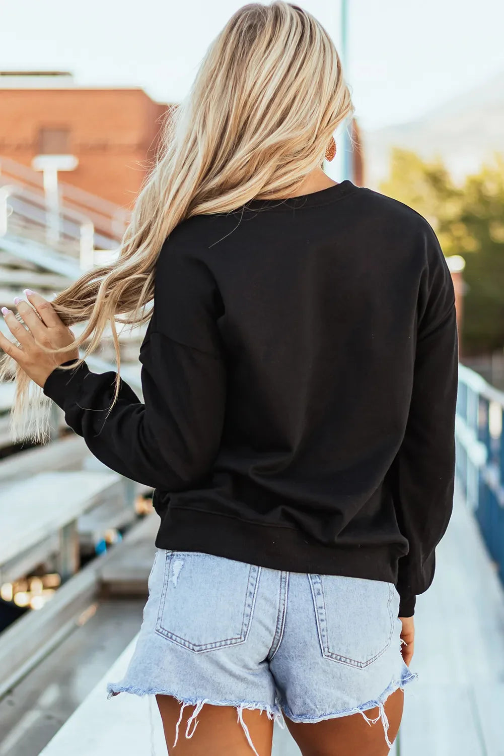 Black crewneck sweatshirt with baseball script appliqué detail.