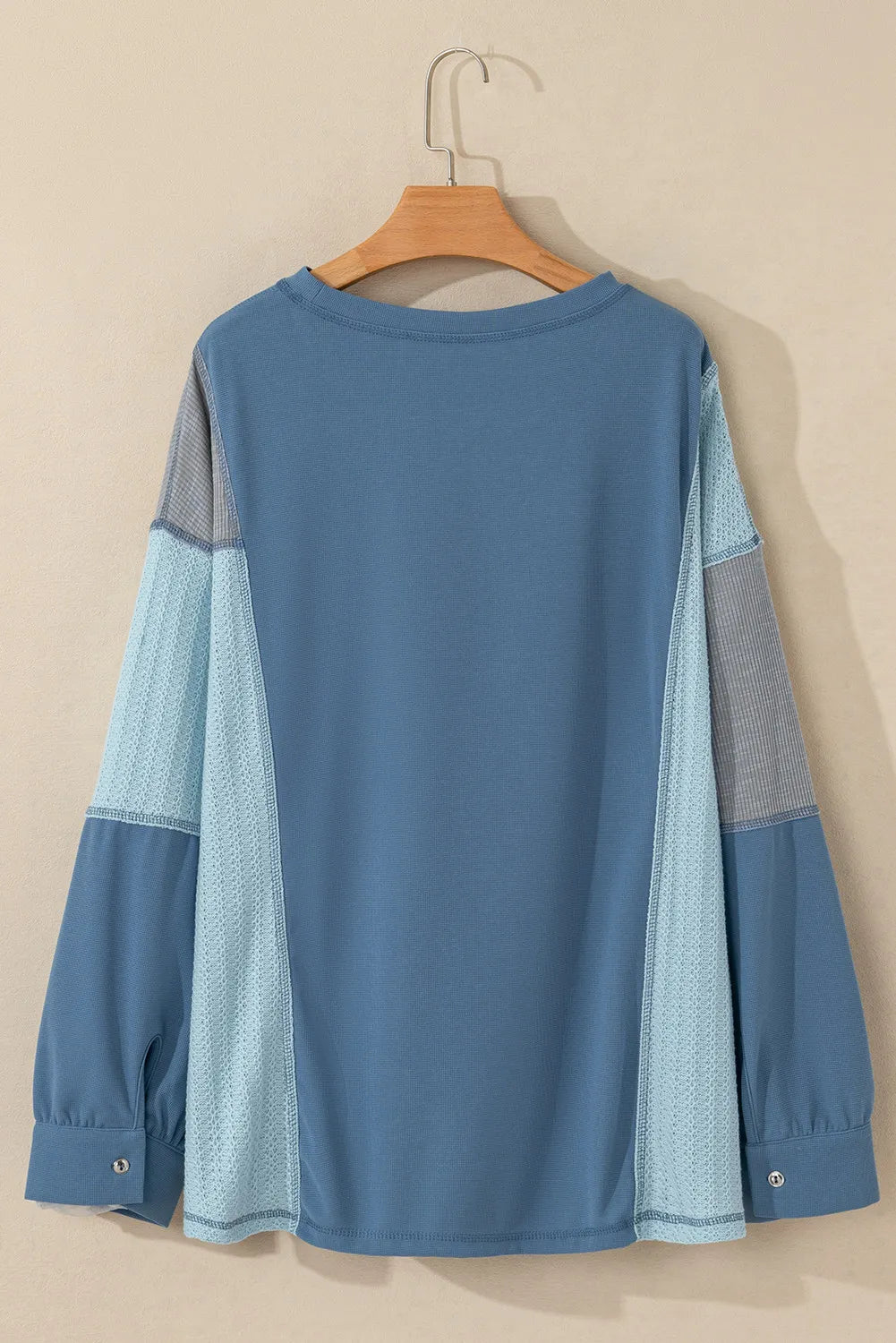 Dusty blue blouson top with waffle knit and mesh panel sleeves.