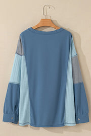 Dusty blue blouson top with waffle knit and mesh panel sleeves.