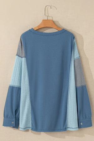 Dusty blue blouson top with waffle knit and mesh panel sleeves.