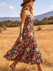 Black floral midi dress with V-neck and tiered skirt, styled with a hat.