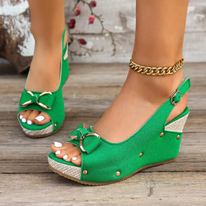 Green peep toe wedge sandals with decorative bow detail and adjustable strap.