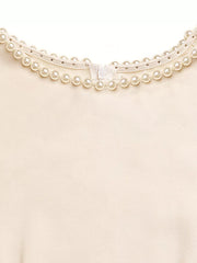 Cream A-line midi dress with pearl and rhinestone neckline detail and zipper closure.