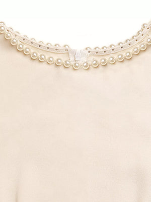 Cream A-line midi dress with pearl and rhinestone neckline detail and zipper closure.