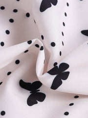 White baby dress with black butterfly and polka dot print.