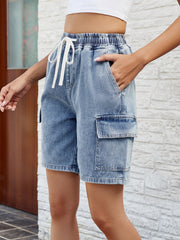 Denim cargo shorts in dusty blue with elastic drawstring waist and utility pockets.