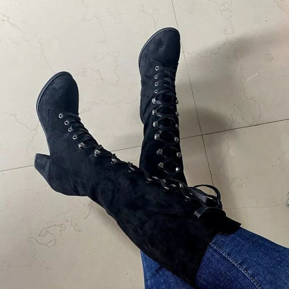 Black suede lace-up block heel boots with silver eyelets and ties.