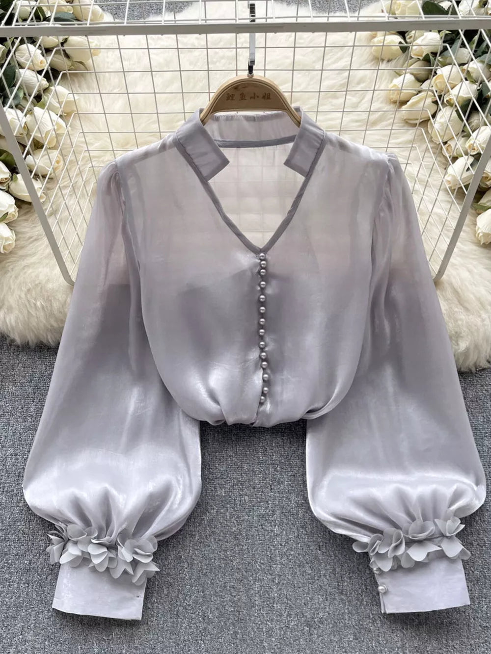 Gray sheer button-down shirt with pearl buttons and floral appliqué cuffs.