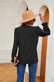 Black perforated blouse with ruffle cuffs and long sleeves.