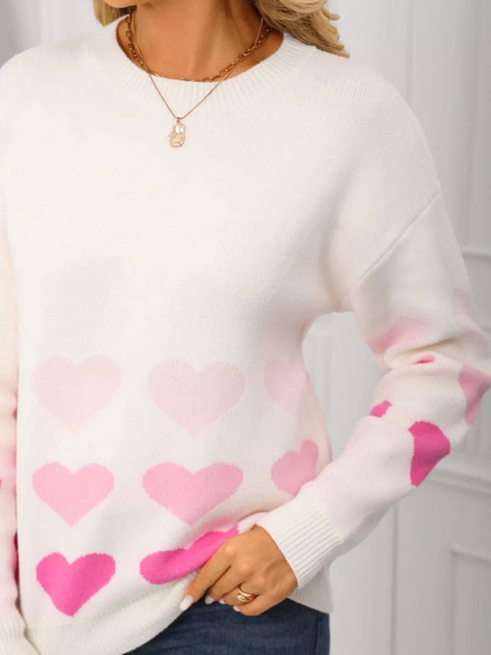 White acrylic crew neck sweater with allover pink heart print and ribbed cuffs.