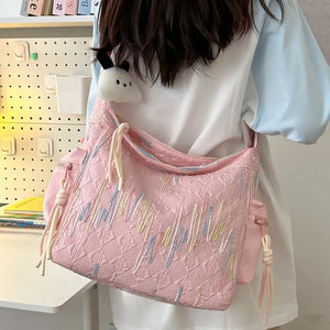 Pink slouchy shoulder bag with embroidered detail and tassel accents